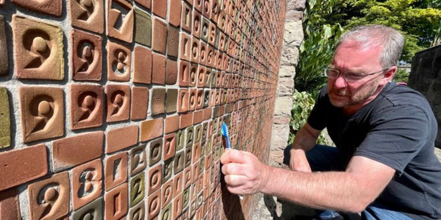 Mark Wylie cleaning the graffiti from Robert Ballagh and Steven Pearse's Troubles Memorial